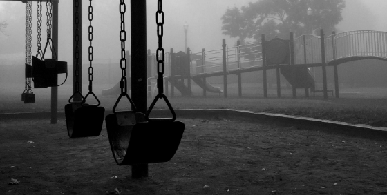 Taman bermain kosong berkabut dengan ayunan yang sepi